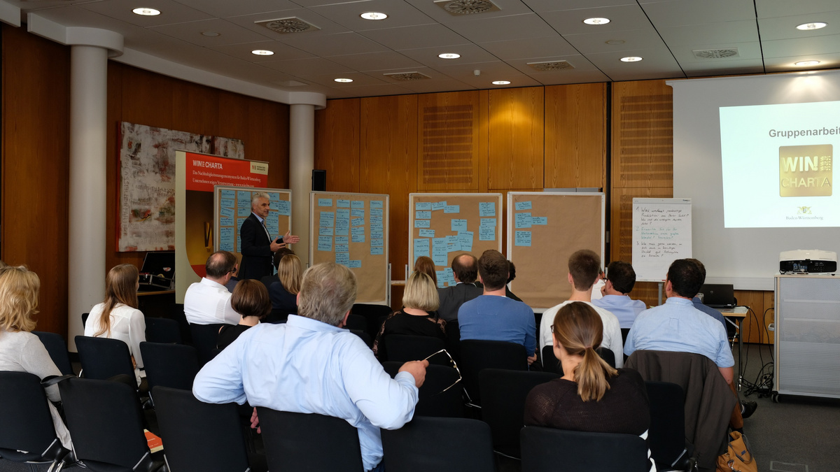 Teilnehmende des WIN-Workshop 2018 sitzen in einem Saal und hören einer Präsentation zu.