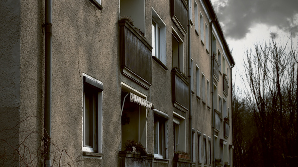 Dargestellt ist eine graue und ungepflegte Fassade eines Mietshauses.