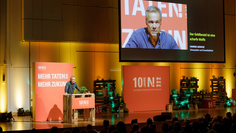 Link führt auf Übersichtsseite der N!-Veranstaltungen; Bild: Auf der Bühne des Jubiläumskongresses "10 Jahre Nachhaltigkeitsstrategie Baden-Württemberg" spricht Hannes Jaenicke zum Publikum. Auf der Bühne des Jubiläumskongresses "10 Jahre Nachhaltigkeitsstrategie Baden-Württemberg" spricht Hannes Jaenicke zum Publikum.