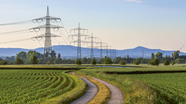 Dargestellt ist eine Hochspannungsleitung in einer hügeligen Landschaft.