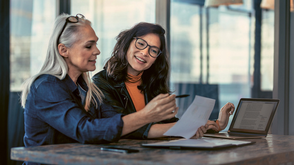 Dargestellt ist eine ältere Frau, die mit einer Mitarbeiterin etwas analysiert.