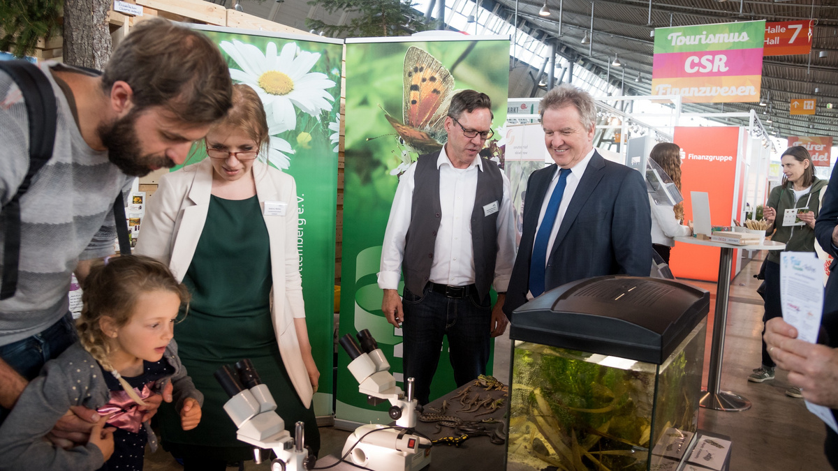 Minister Untersteller, Aussteller und Besucher der Erlebniswelt stehen an einem Messestand.