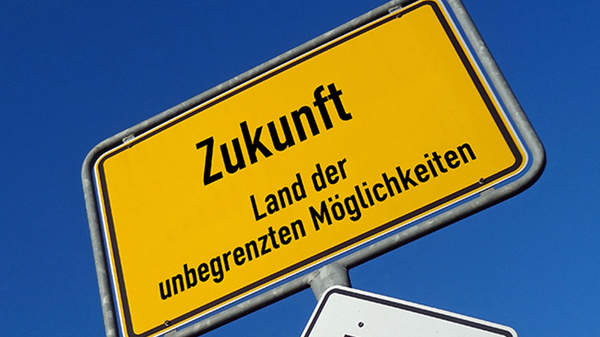 Ein Ortseingangsschild vor einem dunkelblauen Himmel trägt statt eines Ortsnamens die Aufschrift "Zukunft, Land der unbegrenzten Möglichkeiten"..