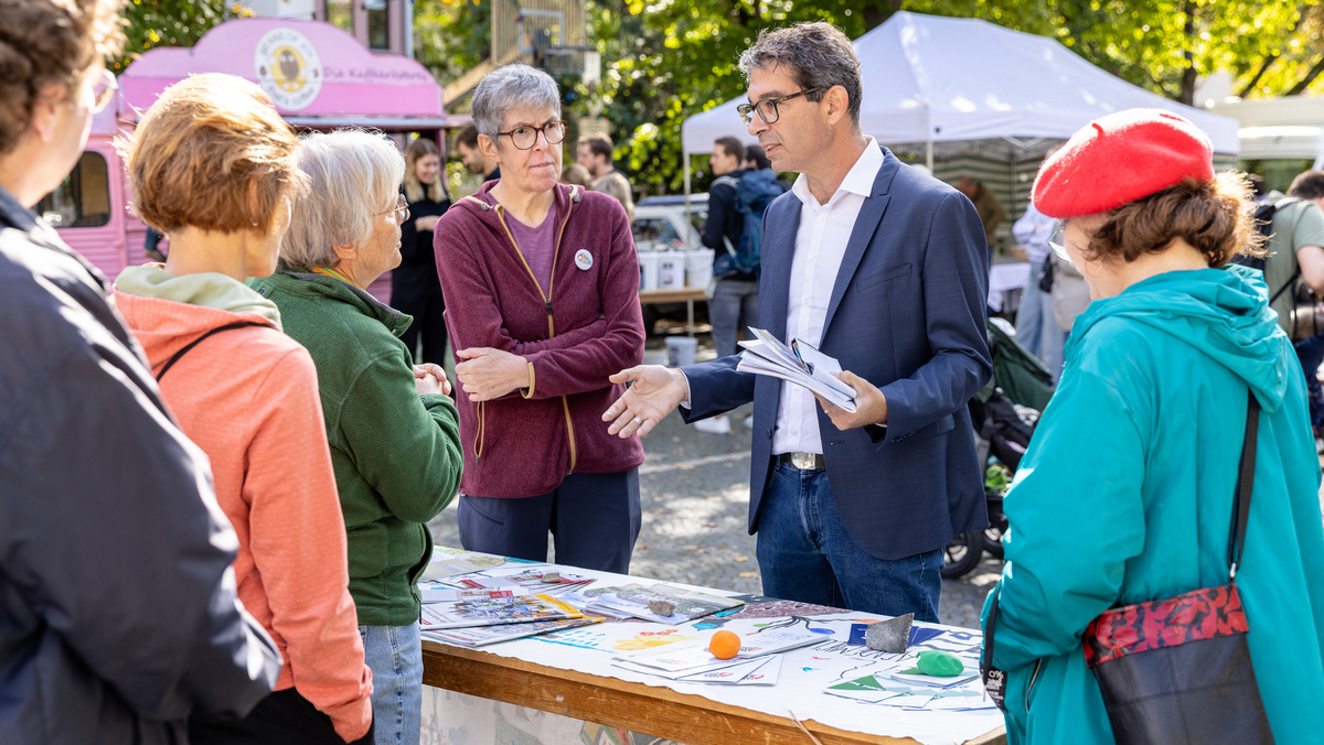 Staatssekretär Dr. Baumann befindet sich auf einem Nachhaltigkeitsmarkt im Gespräch mit einer Gruppe Frauen.