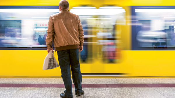 Dargestellt ist eine Person am U-Bahnsteig und eine vorbeifahrende U-Bahn.