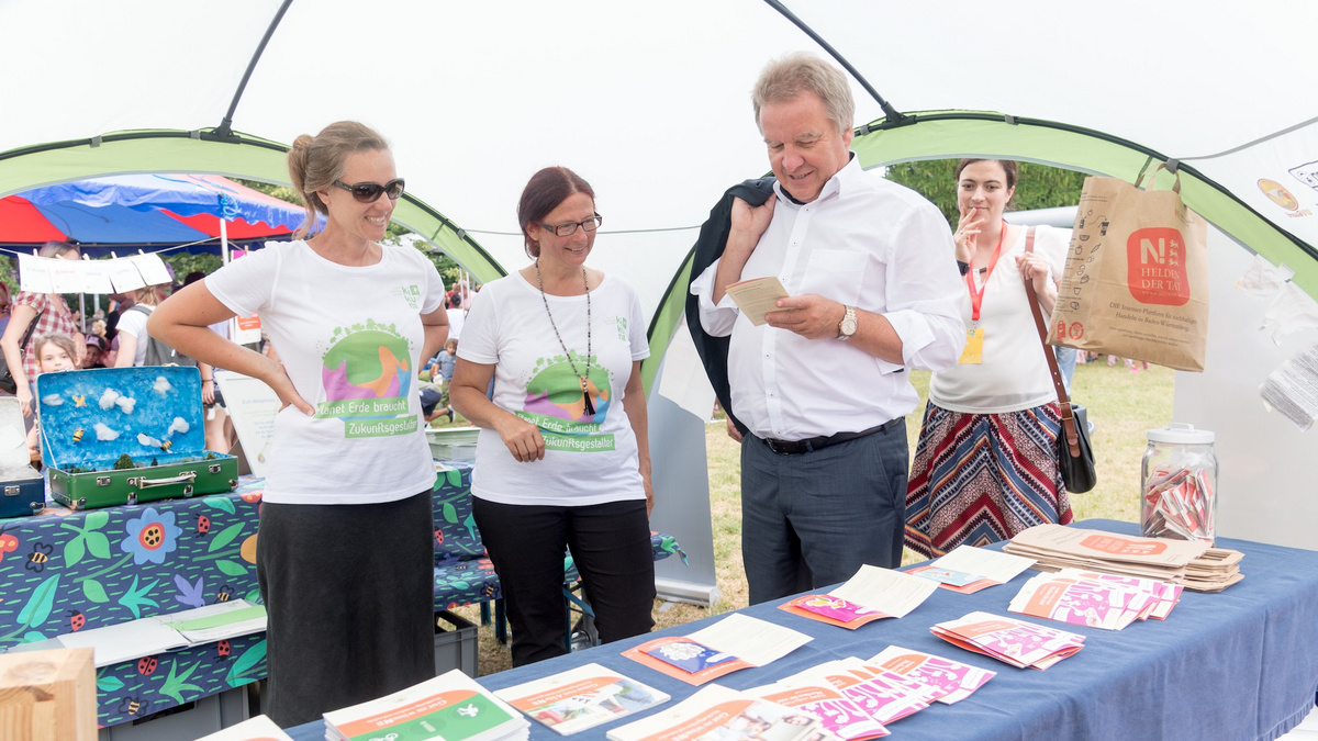 Drei Frauen und Minister Untersteller schauen sich eine Broschüre von einem Auslagetisch an.
