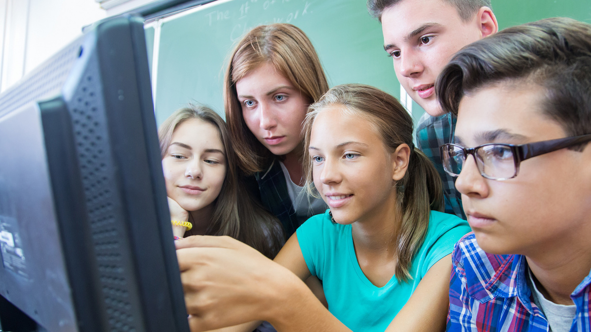 Gemeinsam Wissen erarbeiten Drei Schülerinnen und zwei Schüler drängen sich um eine Computer und schauen gespannt auf den Bildschirm.
