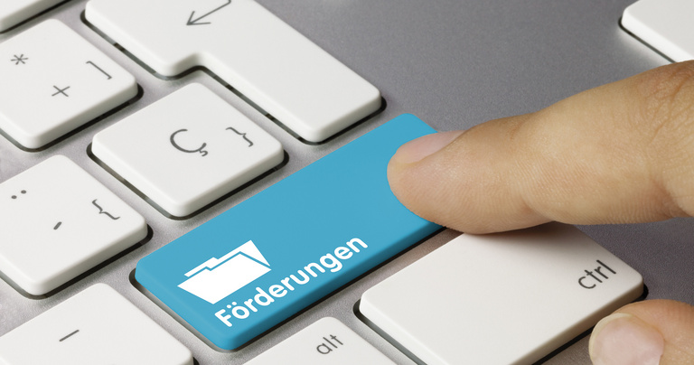 Tastatur mit einer Taste "Förderungen" und einem Finger, der auf diese Taste drückt.