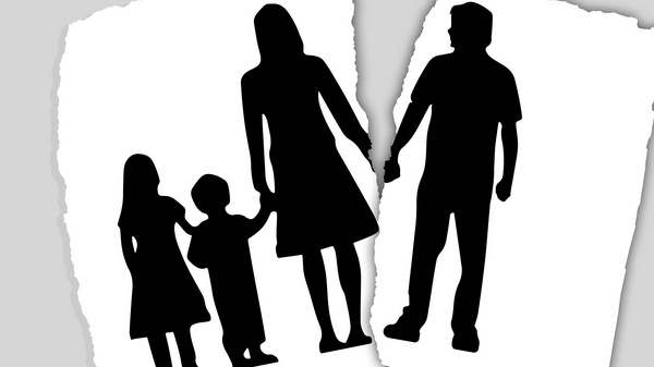 Scheidung mit Kindern Ein ausgefranstes Papierblatt mit dem Scherenschnitt einer Familie ist zerrisen. Auf einem Teil sieht man den Vater der Familie auf dem anderen die Mutter mit einem Mädchen und einem Jungen.