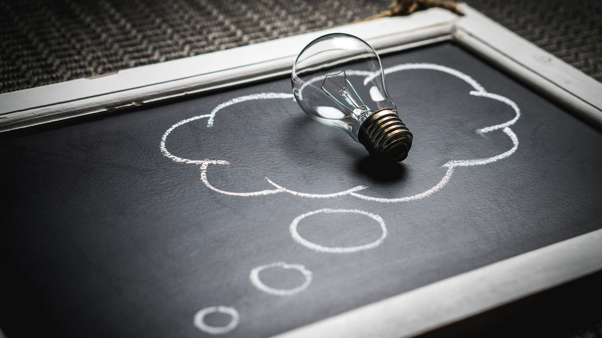 Auf  einer alten Tafel ist eine Gedankewolke aufgemalt. Auf dieser liegt eine Glühbirne.