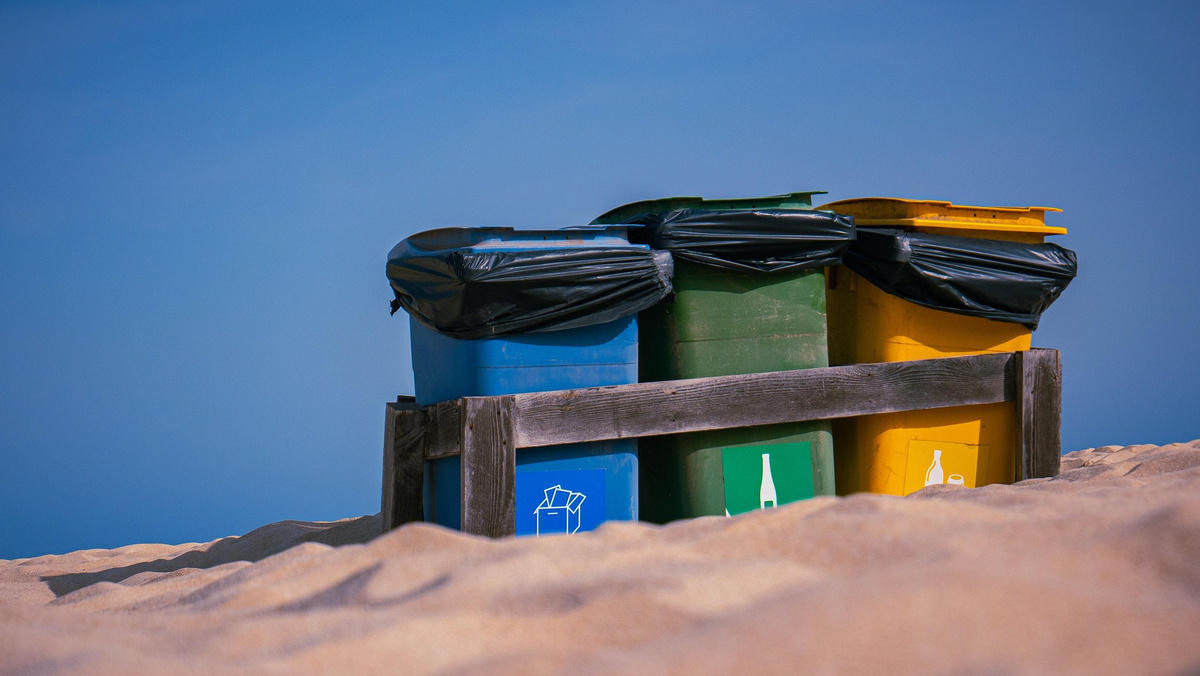 3 Mülleimer am Strand in der Reihenfolge blaue, grüne und gelbe Tonne