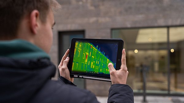 Junger Mann hält ein Tablet mit einer Wärmebildkamera